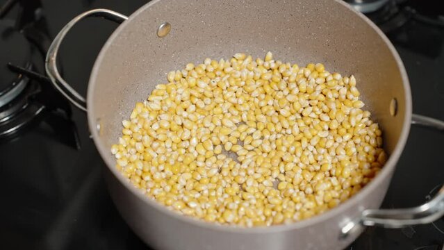 Corn kernels are heated in a large pot on the gas stove, homemade popcorn.