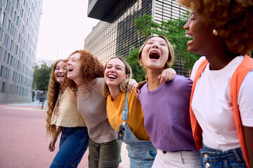 Multiracial only women youth group walk and hug together city outdoors, diverse students and friends laughing. Happy carefree smile celebrating holidays. Girl power, Unity, complicity and community
