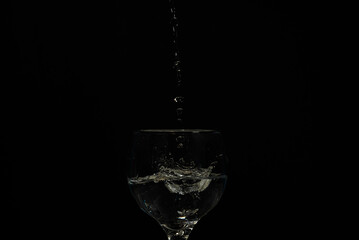 Water falling from above into a wine glass.