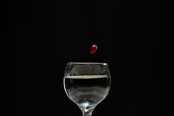 Grape falling from above into a wine glass.