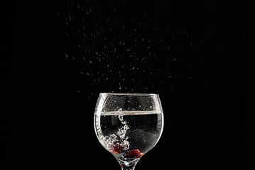 A glass of wine with water and red grapes inside.