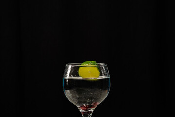 A band of lemon falling into a wine glass with water. Splash effect.