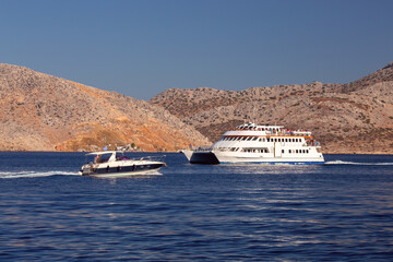 Tourist boats in a blue bay against the backdrop of mountains. - 772603197
