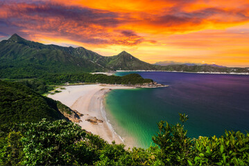 Twilight Landscape with Vibrant Sky, Serene Bay, White Sand Beach, and Lush Green Hills