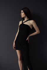 Fototapeta premium An elegant woman captured in a poised stance, wearing a chic black evening dress that embodies sophistication and style, perfect for upscale events and luxury settings.