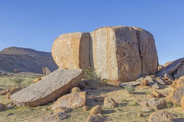 Giant split boulder in the south Namibian desert landscape under a clear blue sky