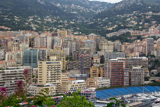 Overlooking the Monte Carlo marina, this image captures a collage of modern and traditional buildings amid lush hills, with yachts docked below