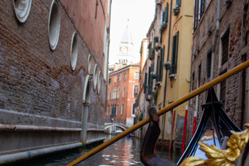 The intimate perspective from a gondola navigating a narrow, secluded canal in Venice, edged by the...