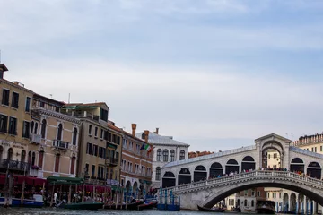 Photo sur Plexiglas Pont du Rialto The iconic Rialto Bridge stretches over Venice's Grand Canal against a backdrop of historic buildings and vibrant street life, a testament to Venetian heritage.