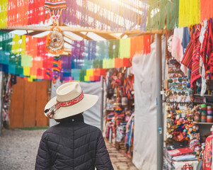 Young woman traveler in hat walks through market typical city in Cusco, Peru. Copy space