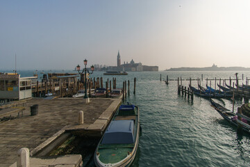 View over pier and boats at Canal Grande to San Giorgio Maggiore Church on a hazy winter day,...