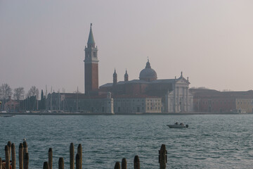San Giorgio Maggiore Church with wooden post from piers in foreground on a hazy winter day, Venice,...