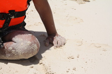 Acercamiento de niño sentado en la arena. 