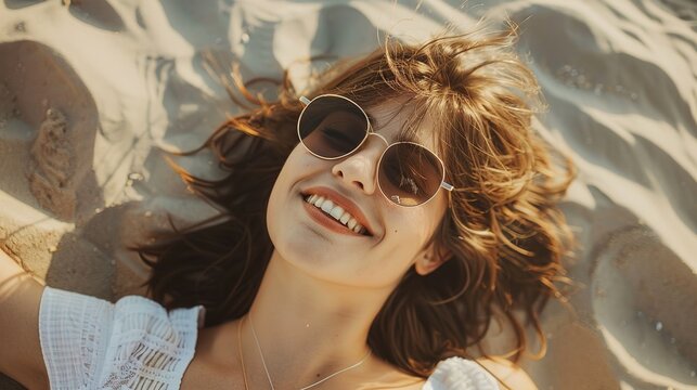 A relaxed portrait of a beautiful smiling brunette young natural woman wearing sunglasses, lounging on a sandy beach, radiating a carefree vibe ai generated high quality image