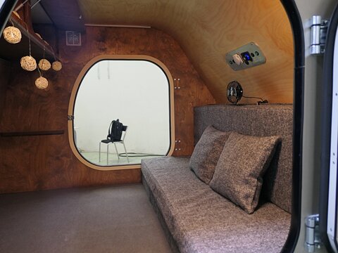Interior of simple sleeping trailer camper van Scout Johny, with pillows and some mattress, paper bulb light chain and basic plugs mounted on the wall. Displayed on caravan expo in Nitra, Slovakia.