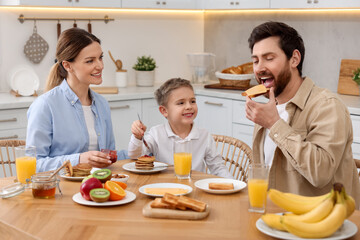 Happy family having breakfast at table in kitchen