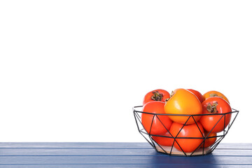 Delicious ripe juicy persimmons in basket on wooden table against white background