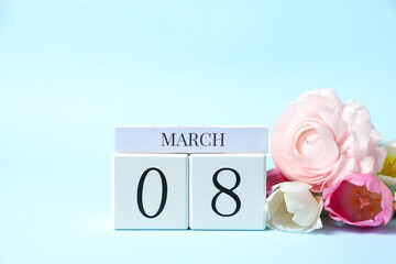 International Women's day - 8th of March. Wooden block calendar and beautiful flowers on light blue background. Space for text