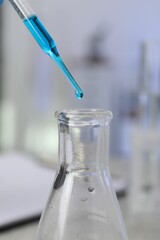 Laboratory analysis. Dripping liquid into flask on table, closeup