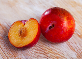 Naklejka na ściany i meble Tasty ripe red plum on a wooden surface. Healthy fruits