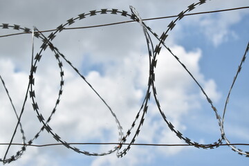 Barbed wire blocking the blue sky with clouds at studio