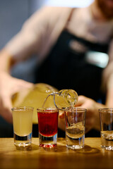the barman pours multicolored alcoholic shots