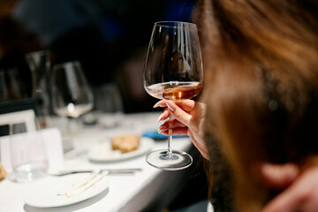 Obraz premium people hold glasses of white and red wine in a night restaurant, celebrating
