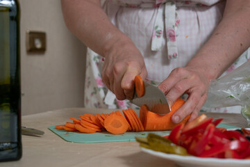 Women's hands cut carrots into slices at studio