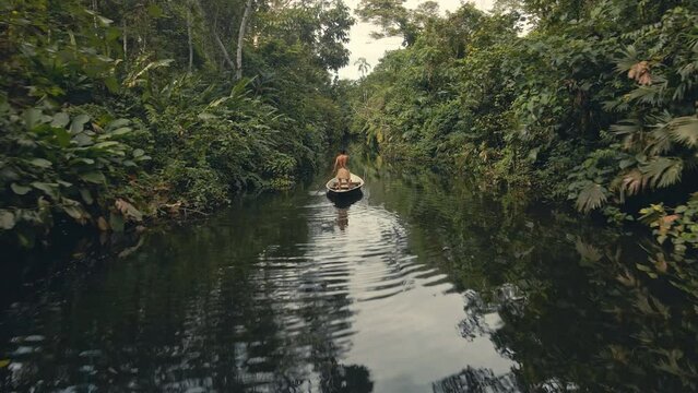 Back drone shot of a tribe man in a canoe