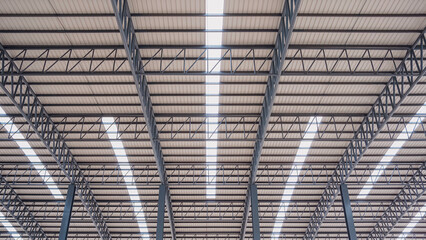 Curve metal roof beam structure with aluminium steel roof and skylights inside of large industrial factory building, Geometric architecture background, low angle and symmetric view