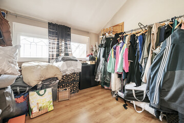 A room cluttered with clothes and stacked boxes