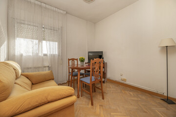 Corner of a small living room with round wooden table with matching chairs upholstered in blue microfiber