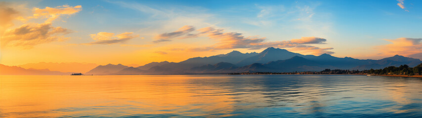 Fototapeta premium Golden Sunrise Over Mountains Reflected in Calm Sea Waters