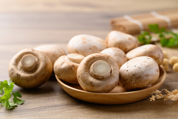 Fresh Champignon mushroom or button mushroom in bowl on wooden background