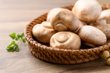 Fresh Champignon mushroom or button mushroom in natural basket on wooden background