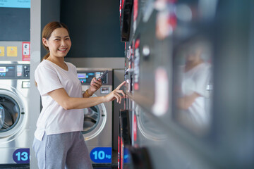 Woman engaging self-service washing machine vendor KIOSK.  - obrazy, fototapety, plakaty