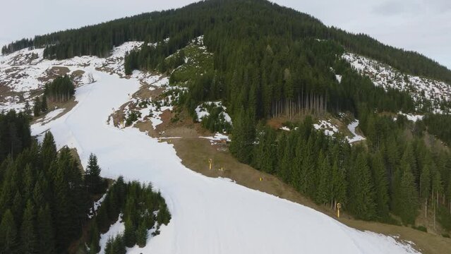 Aerial shot of Saalbach-Hinterglemm ski resort in Austria with melting snow, showing the transition from winter to spring, ascending view