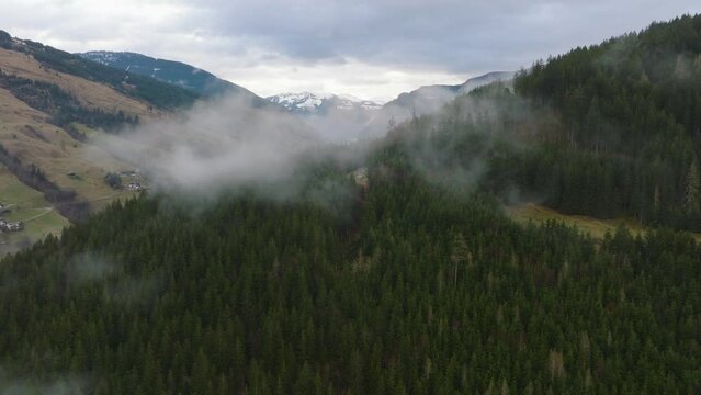 Misty forested mountains with snow peaks at Saalbach-Hinterglemm (Austria), aerial view