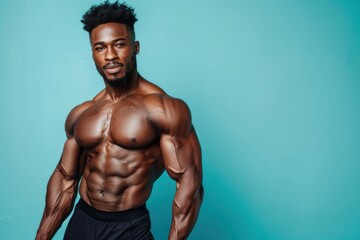 African American male fitness model posing, blue studio background.