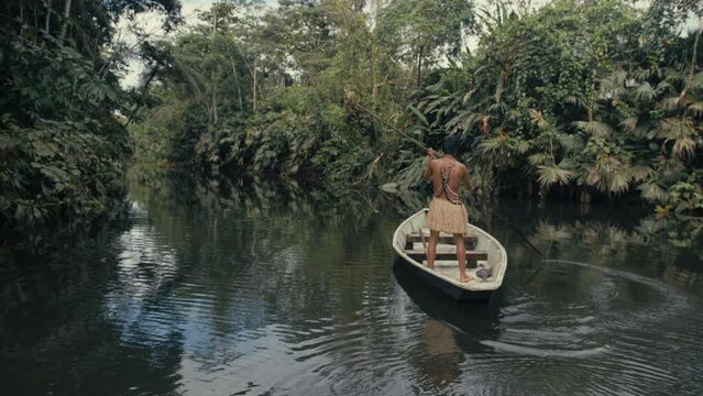 Huaorani boy in a canoe hunting in the rainforest