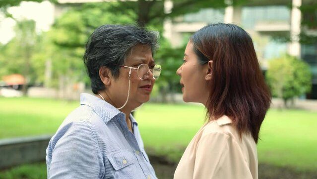 Two women arguing : Elderly woman and younger woman stand arguing with each other angry and loud upset and dissatisfied looking at each other to vent their negative emotions in a public 