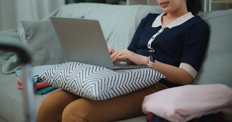 Selective focus hands of Asian teenager woman sitting on sofa using laptop for prepare booking hotel and airplane ticket for travel. backpacker travel concept. - 772699712