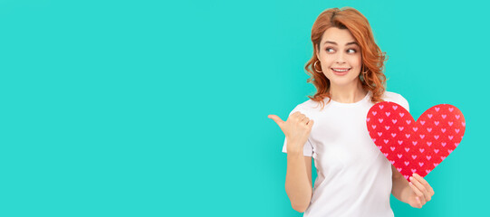 young woman with red heart on blue background. directing thumb up on copy space. Woman isolated face portrait, banner with mock up copyspace.
