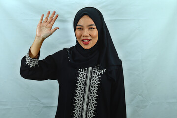 beautiful young Asian Muslim woman wearing hijab and black dress with white pattern tell say hello...