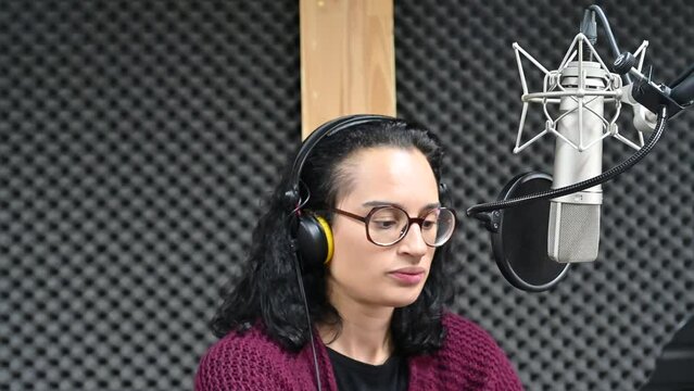 Jeune femme chantant dans un studio d'enregistrement