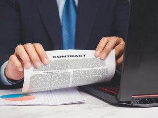 Businessman tearing up a contract agreement while sitting at a desk. - obrazy, fototapety, plakaty