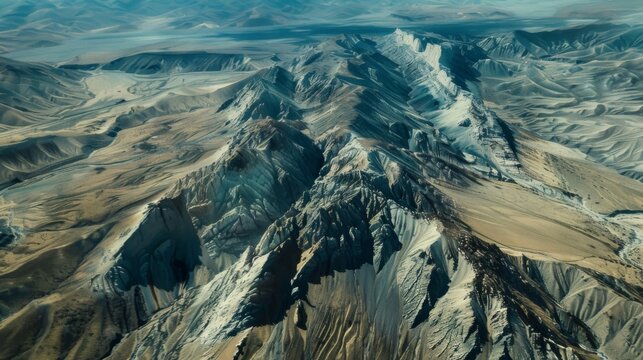 A striking aerial shot of a remote mountain range with a series of craggy peaks and valleys that look like they were carved by the hand of an ancient titan.