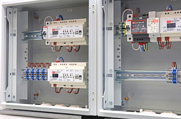 An electric switchboard with modules for protection and control of electrical loads, mounted on din rails. - obrazy, fototapety, plakaty