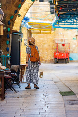 Fototapeta premium Beautiful girl traveler in a hat and with a backpack exploring the historical city.