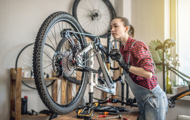 Woman fixing a mountain bike in a workshop. Concept of preparation for the new season, repair and maintenance - 772736921